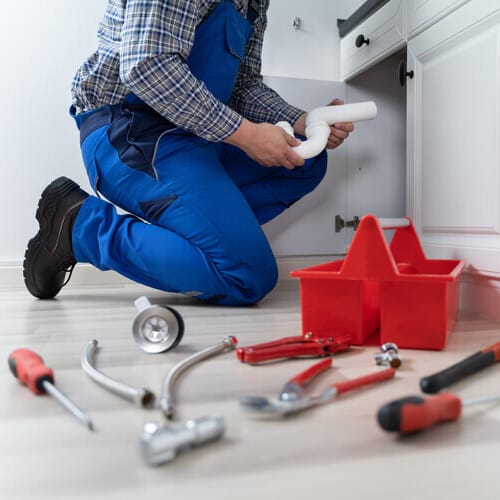 plumber fixing pipes underneath a sink