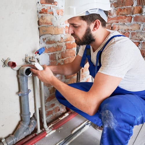 plumber working on pipes in a home