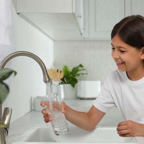 young girl filling a glass of water