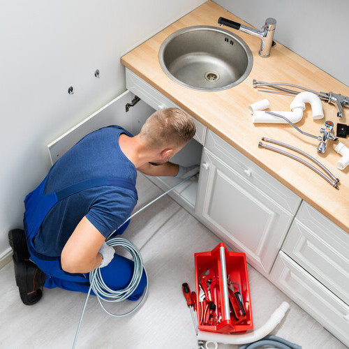 plumber providing drain repair underneath a sink