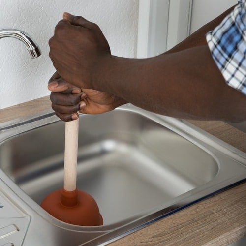 plumber plunging a kitchen sink