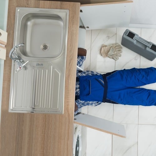 plumber working underneath a sink