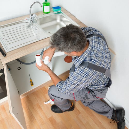 plumber replacing pipes underneath a sink