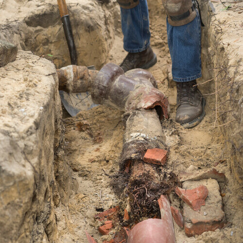 worker repairing a terra cotta sewer line