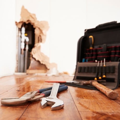 plumber's tools and toolbox next to a water damaged wall