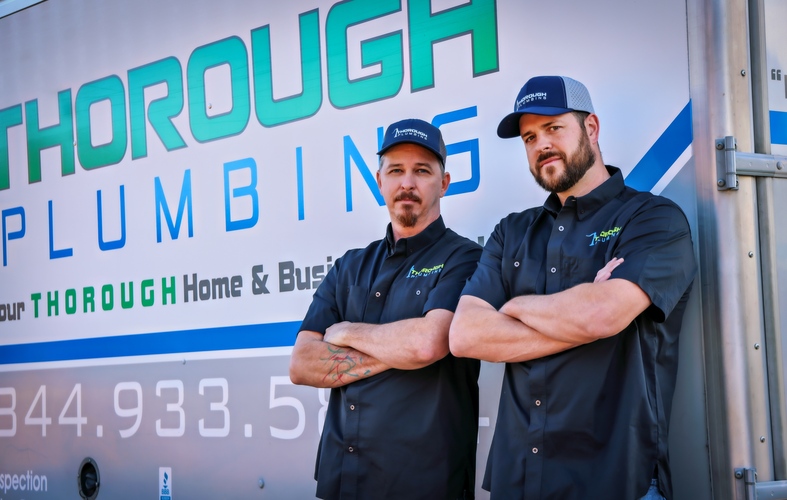 plumbing technicians in front of a plumbing van